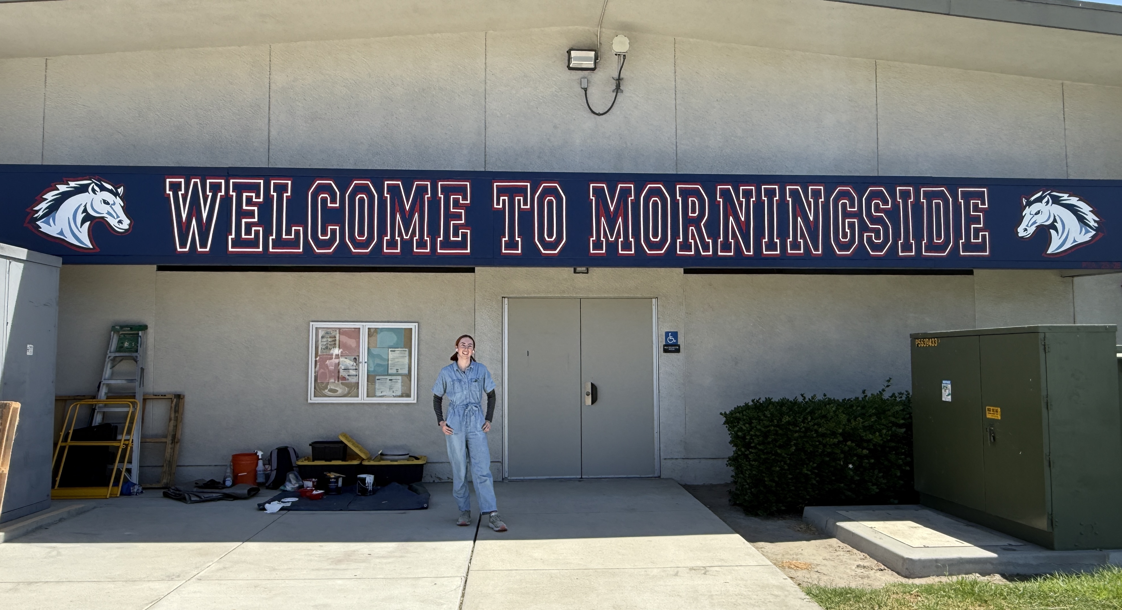 Artist Maya Benham proudly displays our new school banner!